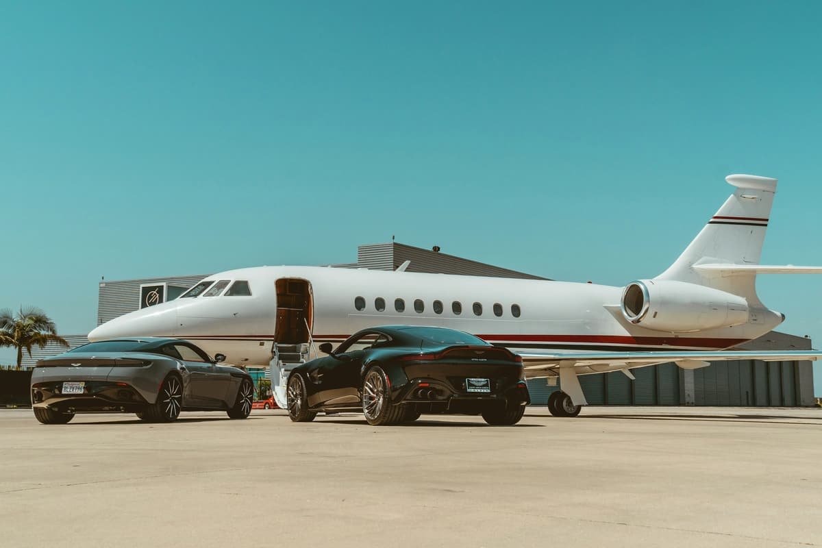 A business jet parked beside black cars on the apron